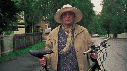 Eine ältere Dame hält ein Fahrrad vor sich