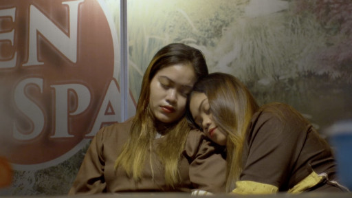 Zwei junge Frauen schlafen. Eine der Frauen hat ihren Kopf auf der Schulter der anderen abgelegt.