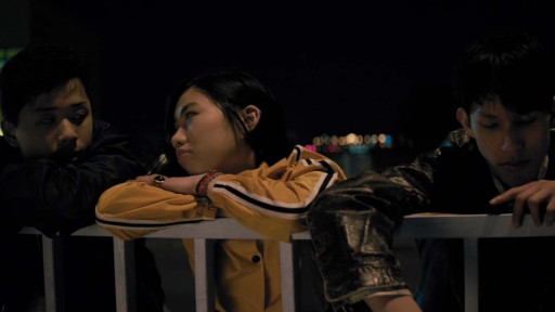 Drei Jugendliche stützen sich in der Nacht gelangweilt auf ein Brückengeländer