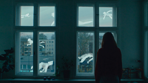 Eine Person schaut aus dem Fenster. Hinter dem Fenster sind weiße gemalte Figuren zu sehen.