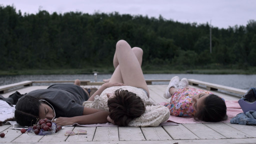 Drei Mädchen liegen auf einem Steg am See